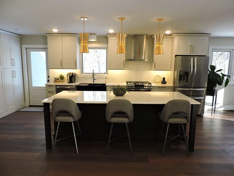 Main floor kitchen in Ada with a dark island, white quartz and brass pendants