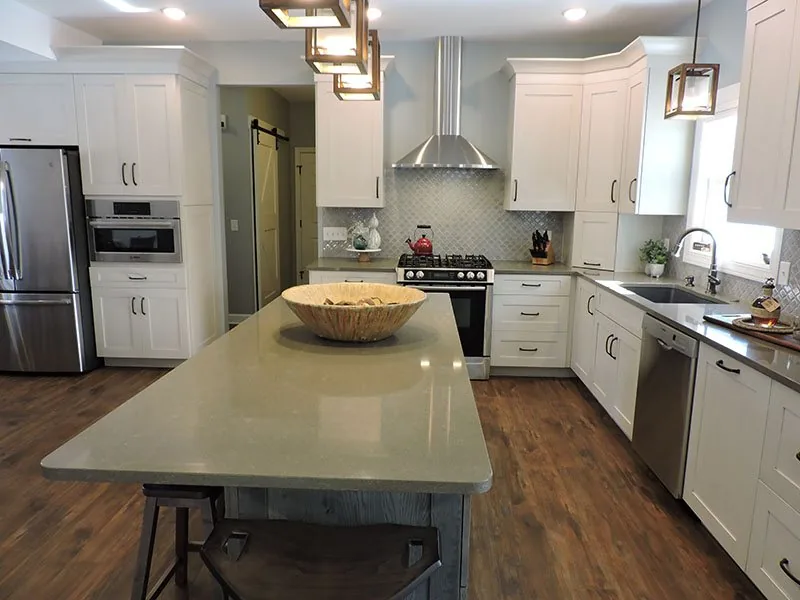 Wide kitchen with white cabinets, a long island and hardwood floors in the Alto house