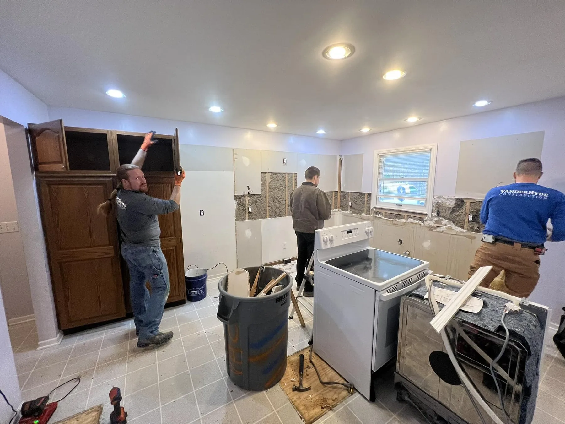 Three VanderHyde Construction team members taking out the old cabinets and backsplash during a kitchen demolition