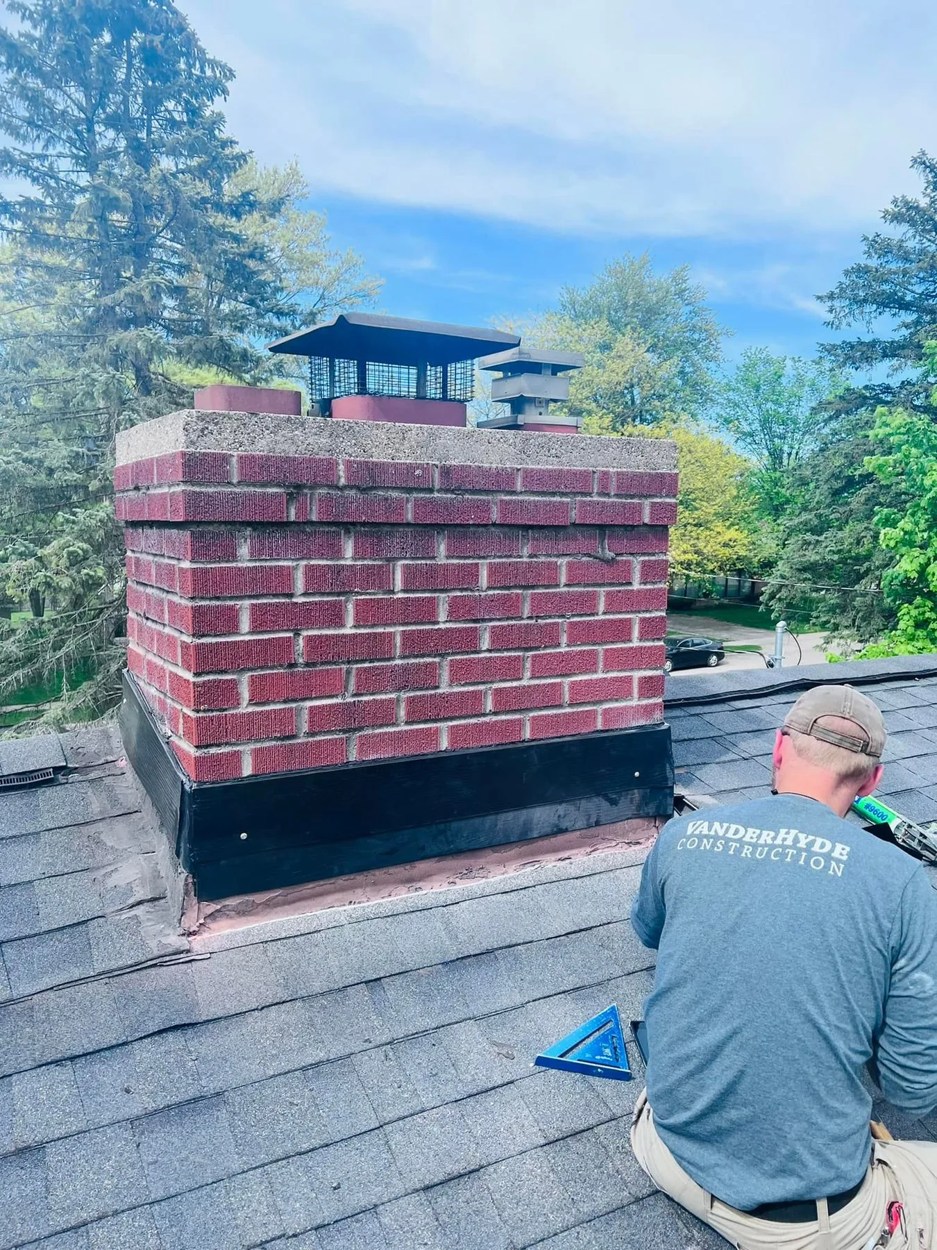 A team member working on a brick chimney on a roof