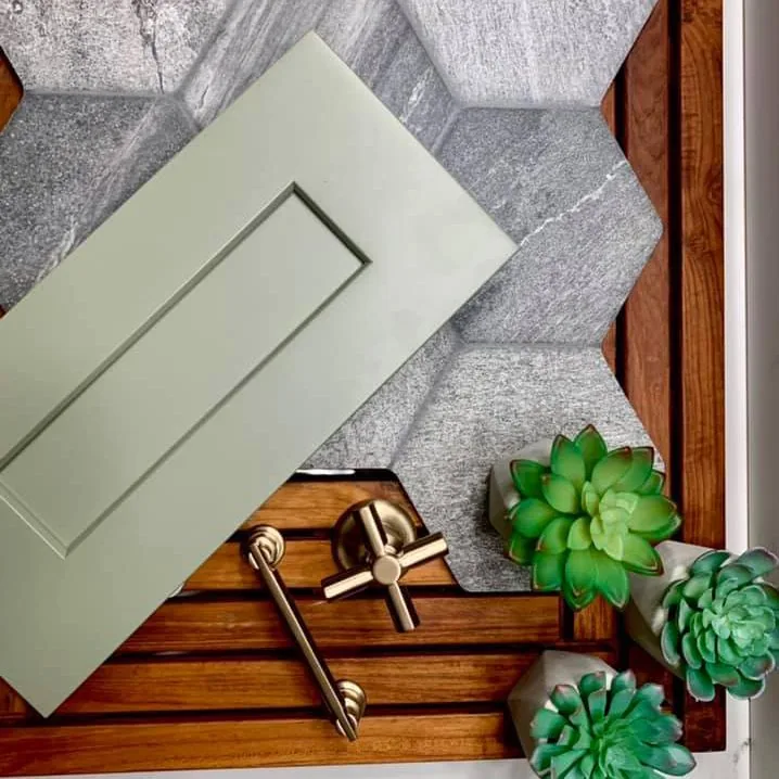 Design materials laid out together, a painted cabinet door, stone samples, wood and cabinet hardware