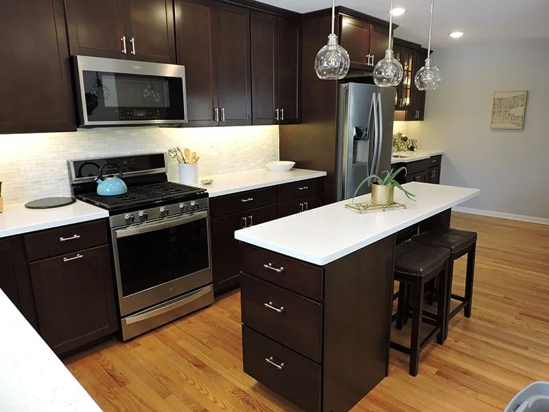Dark espresso cabinets with white quartz counters and an island in the Westside Renovation kitchen